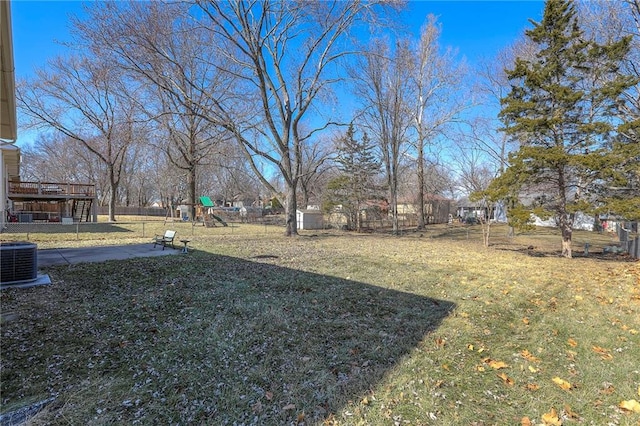 view of yard with a playground, fence, and central AC unit