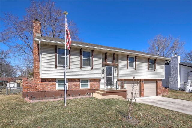 raised ranch featuring a garage, driveway, a chimney, and a front lawn