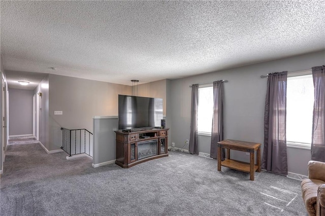 living area with carpet, baseboards, and a textured ceiling