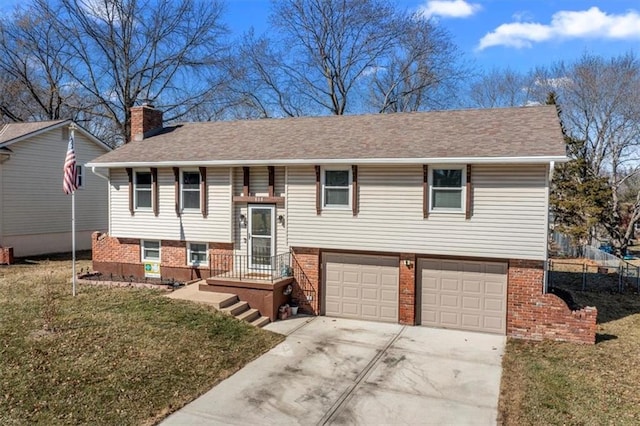 bi-level home featuring a garage, concrete driveway, a chimney, a front lawn, and brick siding