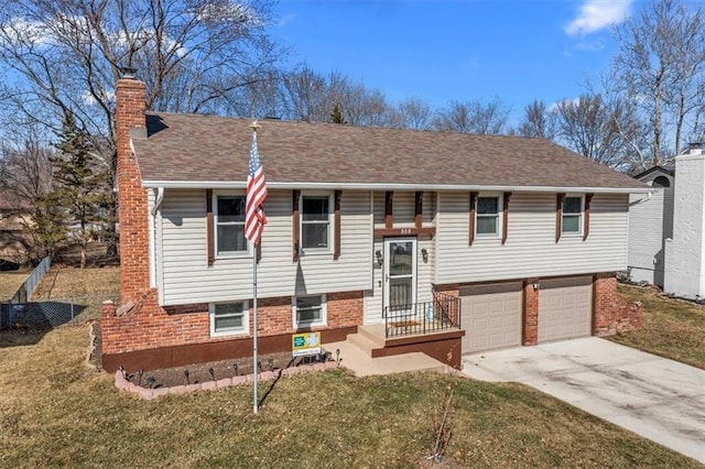 bi-level home with brick siding, a chimney, concrete driveway, an attached garage, and a front yard