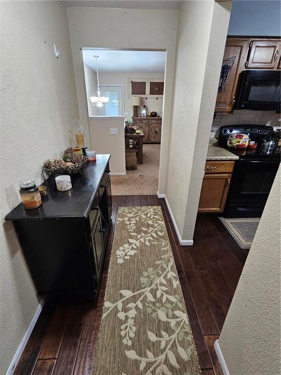 corridor featuring an inviting chandelier and dark hardwood / wood-style flooring