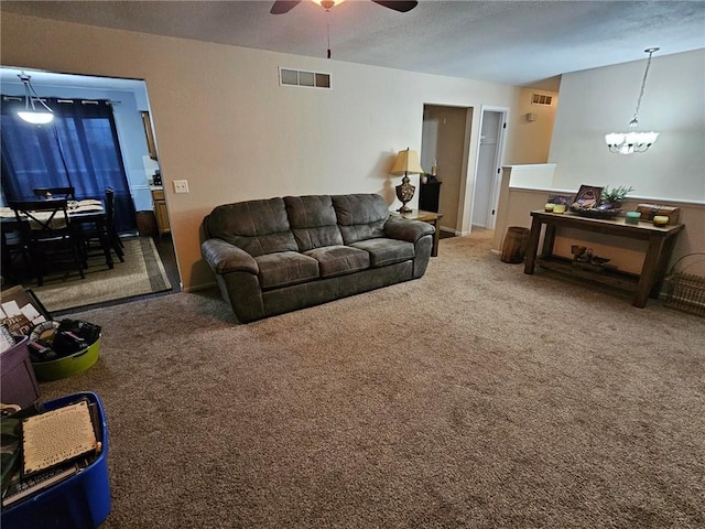 carpeted living room featuring ceiling fan with notable chandelier