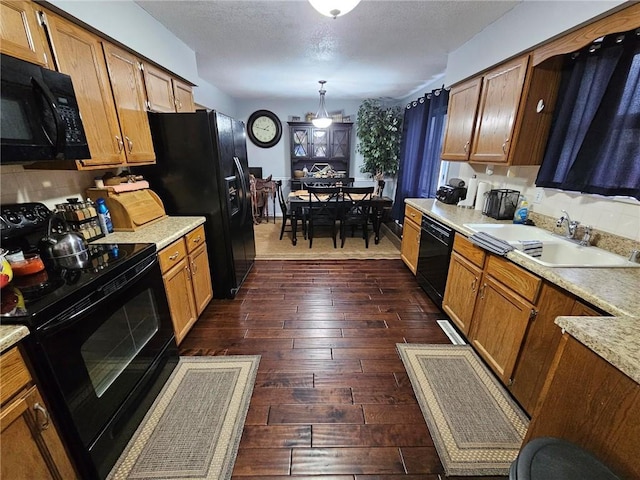 kitchen with sink, black appliances, a textured ceiling, dark hardwood / wood-style flooring, and decorative light fixtures