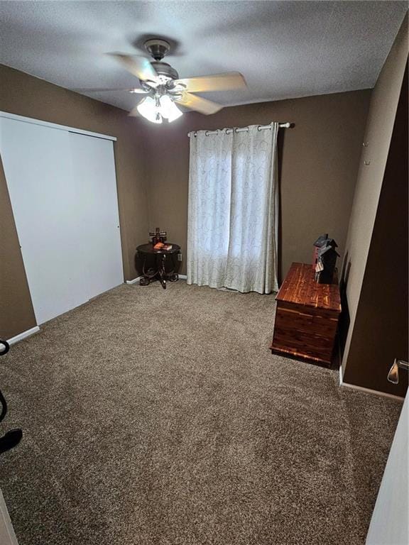 unfurnished bedroom featuring ceiling fan, carpet floors, and a textured ceiling