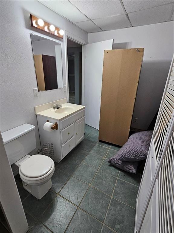 bathroom featuring a paneled ceiling, vanity, and toilet