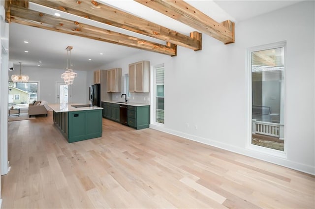 kitchen with a center island with sink, open floor plan, freestanding refrigerator, light countertops, and green cabinetry