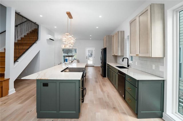 kitchen featuring a kitchen island with sink, a sink, light countertops, hanging light fixtures, and black appliances