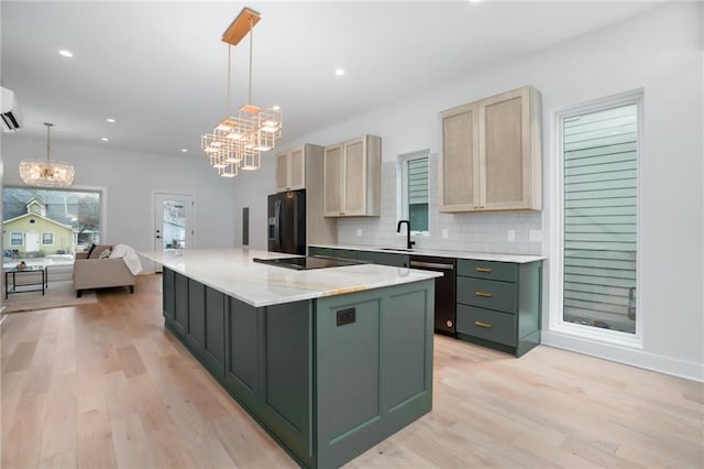 kitchen featuring black appliances, a center island with sink, pendant lighting, and light brown cabinetry