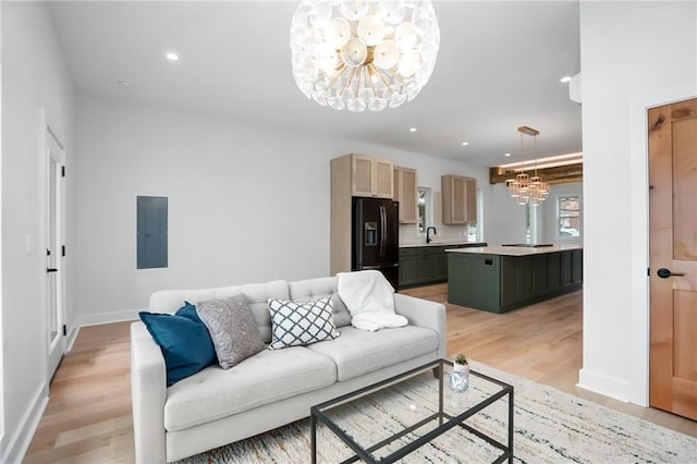 living room with recessed lighting, light wood-style flooring, an inviting chandelier, electric panel, and baseboards