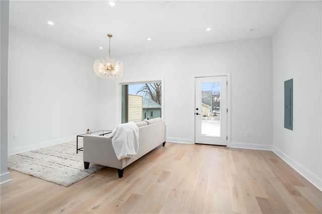 living room with electric panel, baseboards, an inviting chandelier, light wood-type flooring, and recessed lighting