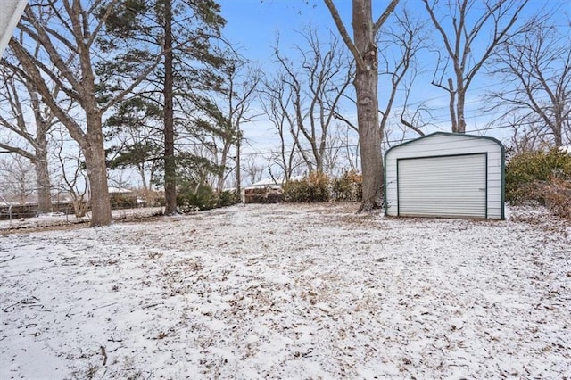 snowy yard with a garage and an outbuilding