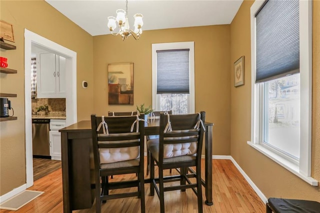 dining space featuring baseboards, a notable chandelier, and light wood-style flooring