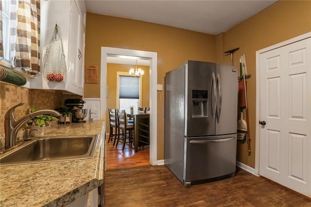 kitchen with tasteful backsplash, a sink, a chandelier, stainless steel fridge, and dark wood-style flooring