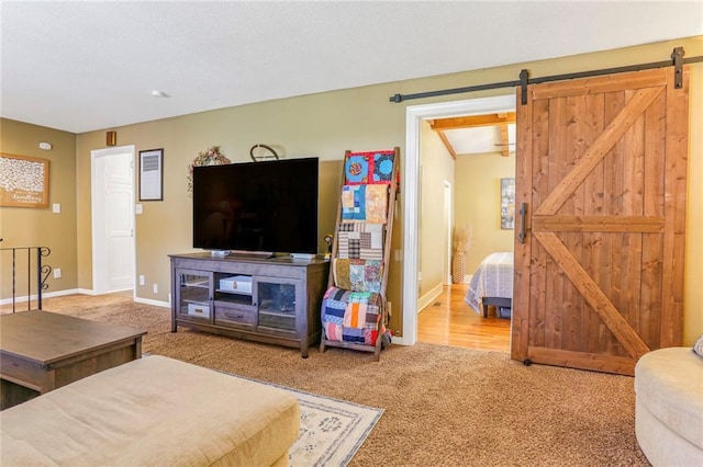 living area featuring a barn door, carpet floors, and baseboards