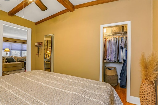 bedroom featuring wood finished floors, baseboards, vaulted ceiling with beams, a closet, and a walk in closet