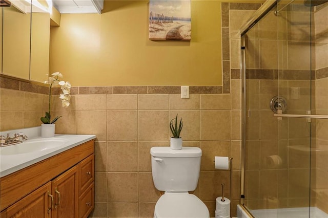 bathroom featuring a shower stall, vanity, tile walls, and toilet