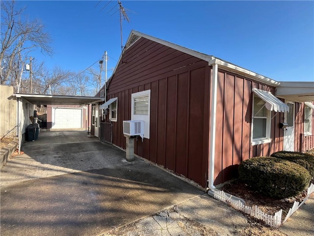 view of property exterior with a carport, board and batten siding, cooling unit, and driveway