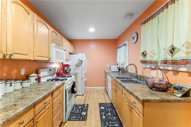 kitchen with light wood-style flooring, white appliances, baseboards, and a sink