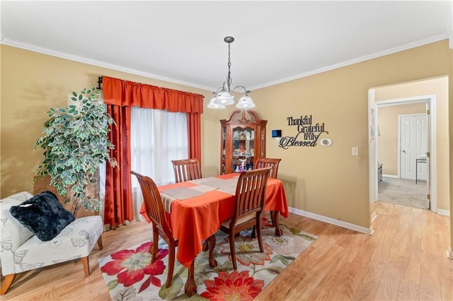 dining room featuring crown molding, light wood-style floors, and baseboards