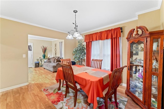 dining area featuring a chandelier, crown molding, light wood-type flooring, and baseboards