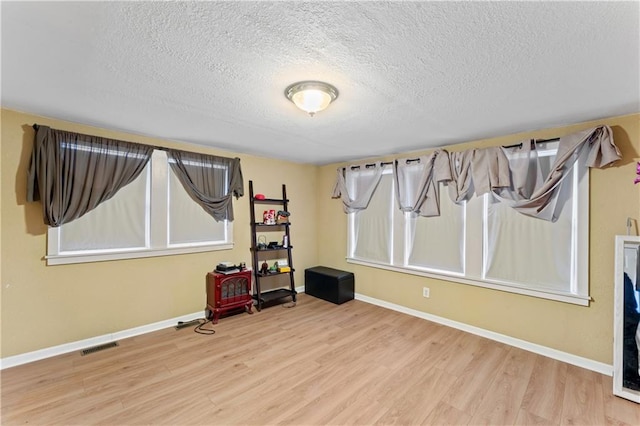 interior space featuring visible vents, wood finished floors, baseboards, and a textured ceiling