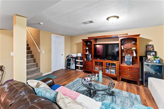 living area featuring visible vents, a textured ceiling, wood finished floors, and stairway