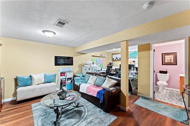 living room with visible vents, baseboards, a textured ceiling, and wood finished floors