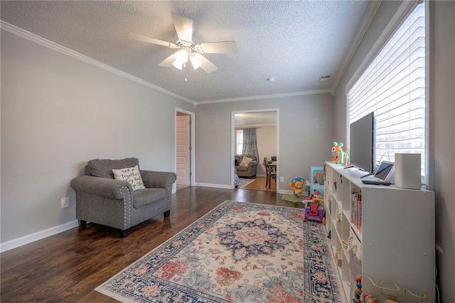 sitting room featuring ceiling fan, dark wood-type flooring, ornamental molding, and a textured ceiling