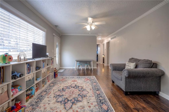 living room featuring ceiling fan, dark wood-type flooring, ornamental molding, and a textured ceiling