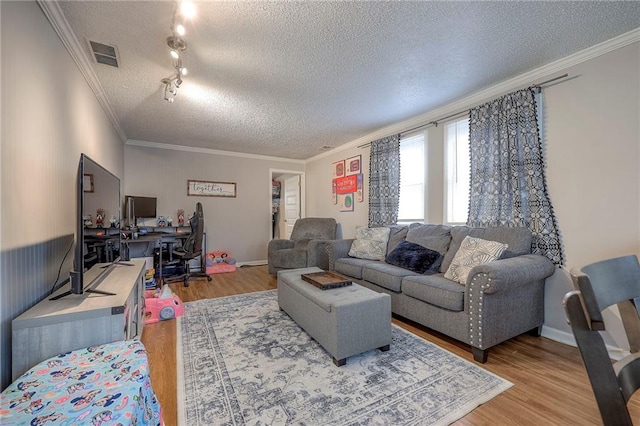 living room featuring hardwood / wood-style floors, track lighting, ornamental molding, and a textured ceiling