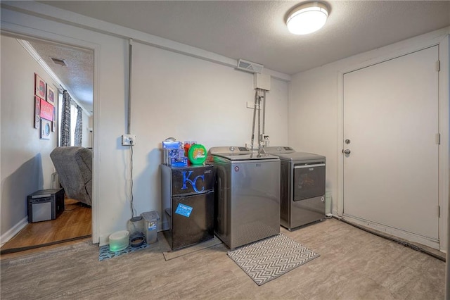 washroom with separate washer and dryer, light hardwood / wood-style floors, and a textured ceiling