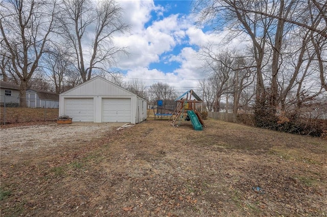 view of yard with an outbuilding, a trampoline, a garage, and a playground