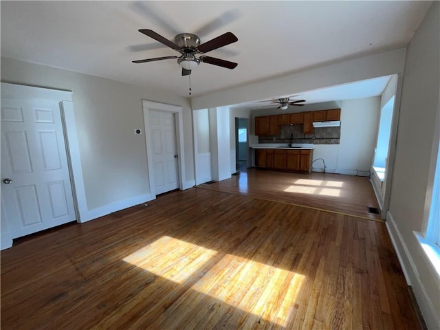 unfurnished living room featuring sink and dark hardwood / wood-style flooring