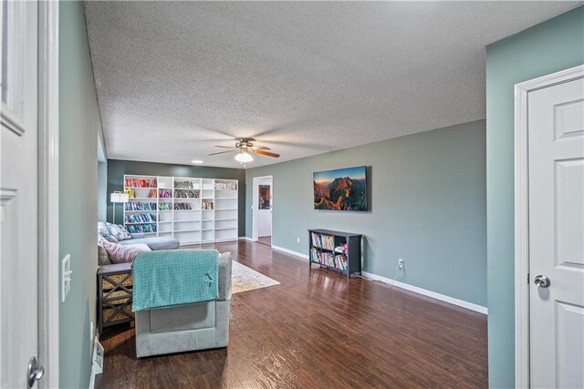 living room featuring dark hardwood / wood-style flooring, ceiling fan, and a textured ceiling