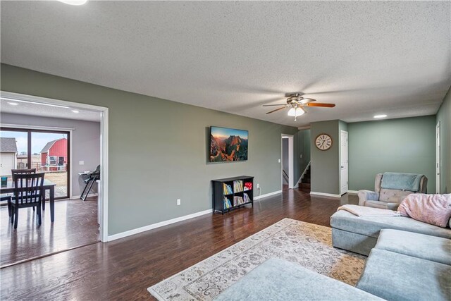 living room with ceiling fan, dark hardwood / wood-style floors, and a textured ceiling