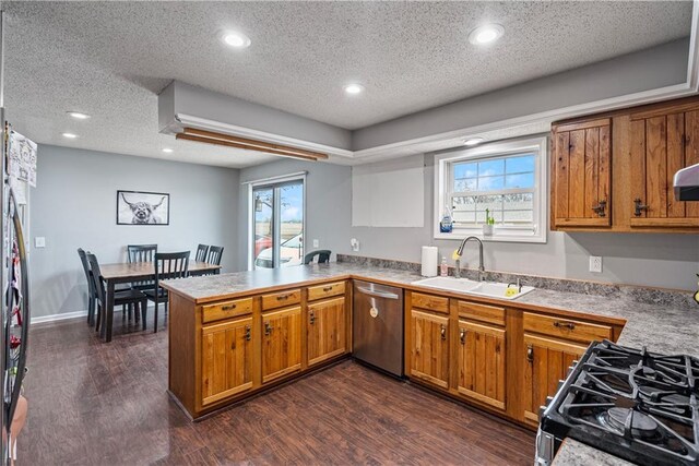 kitchen with sink, stainless steel appliances, dark hardwood / wood-style floors, a textured ceiling, and kitchen peninsula