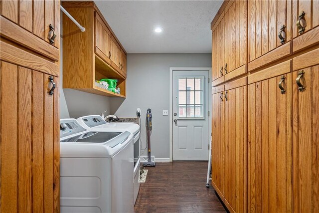 laundry room with dark hardwood / wood-style flooring, washer and clothes dryer, and cabinets