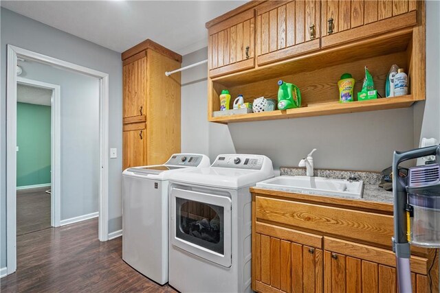 laundry room with cabinets, dark hardwood / wood-style flooring, washer and clothes dryer, and sink