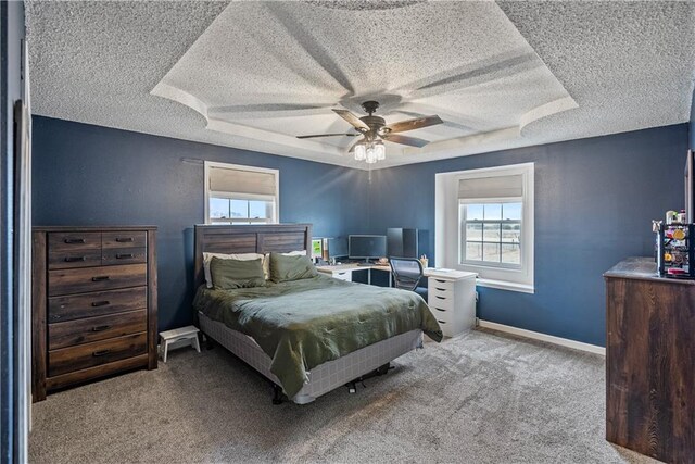 carpeted bedroom featuring a raised ceiling, ceiling fan, and a textured ceiling