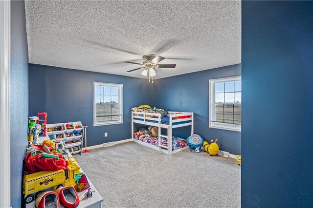 bedroom featuring ceiling fan, carpet floors, multiple windows, and a textured ceiling