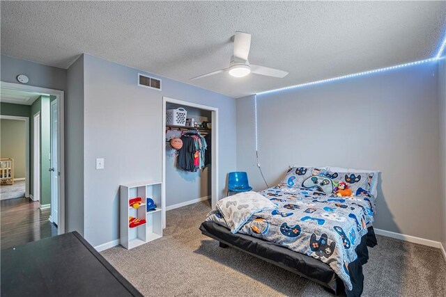 carpeted bedroom featuring ceiling fan, a textured ceiling, and a closet