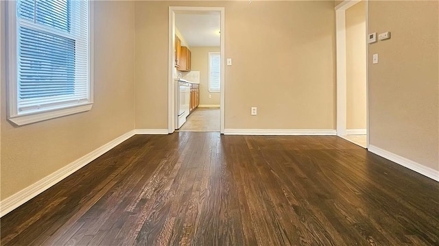 unfurnished room featuring dark wood-type flooring and a healthy amount of sunlight