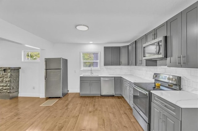 kitchen with gray cabinets, appliances with stainless steel finishes, sink, and backsplash