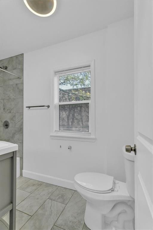 bathroom with vanity, toilet, and a tile shower