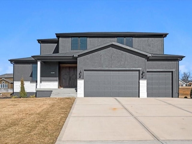 view of front of home featuring a garage, concrete driveway, a front lawn, and stucco siding