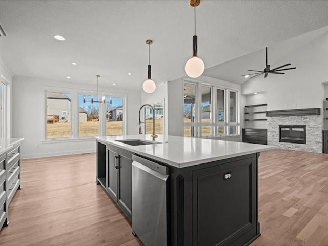 kitchen featuring dark cabinets, a sink, vaulted ceiling, light countertops, and stainless steel dishwasher