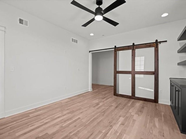 interior space featuring a barn door, visible vents, baseboards, and light wood-style flooring