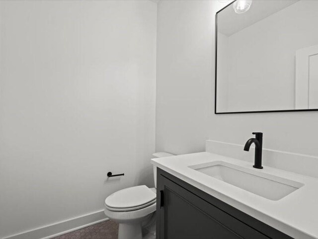 bathroom with toilet, baseboards, and vanity