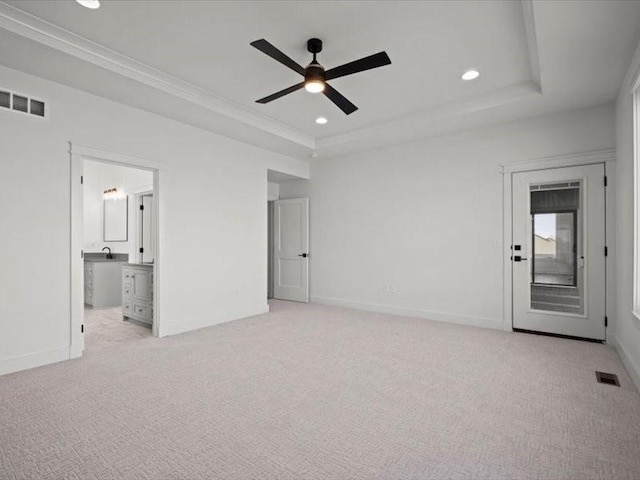 unfurnished bedroom with a tray ceiling, recessed lighting, visible vents, and light colored carpet